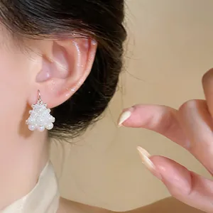 Primo piano di eleganti orecchini di perle a forma di cesto di fiori sull'orecchio