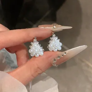 Primo piano di eleganti orecchini a cestino in argento con grappolo di perle bianche.
