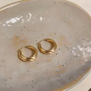 Detail view showing the elegant twisted design of golden hoop earrings with a shiny finish