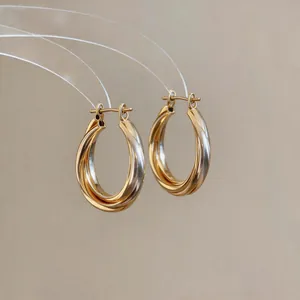 Close-up of minimalist two-tone twisted hoop earrings with gold and silver finish