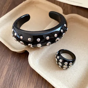 Detailed macro view of black resin cuff bracelet and ring set with silver metal studs