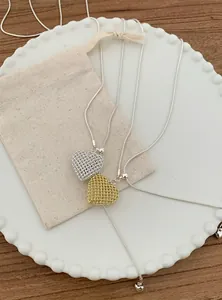 Close-up of elegant hollow-out heart necklaces in silver and gold on a decorative plate