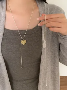 Detail of hollow heart pendant necklaces in gold and silver finishes with Y-style lariat chain