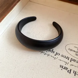 Close-up detail of a minimalist matte black resin open cuff bracelet on a canvas tray.