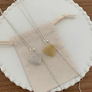 Detailed view of gold and silver hollow mesh heart pendants on dainty snake chains