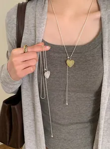 Close-up detail of elegant openwork heart lariat necklace in gold and silver finish