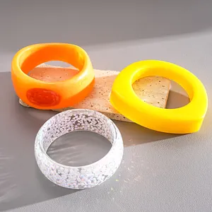 Close-up of vibrant resin geometric bangles in orange, yellow, and iridescent clear