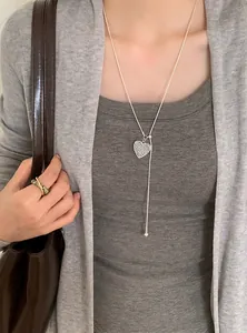 Detailed close-up of a silver hollow heart pendant necklace worn on a lifestyle model.