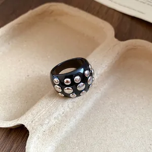 Detail shot of a black resin ring with circular silver studs on a pulp tray background