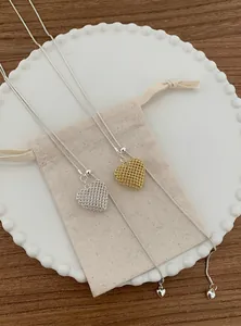 Detailed macro view of two hollow mesh heart pendant necklaces in gold and silver finishes