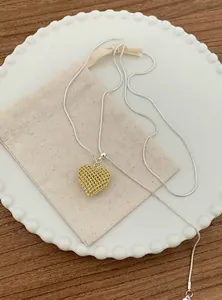 Close-up of a gold hollow heart pendant on a delicate silver snake chain necklace.