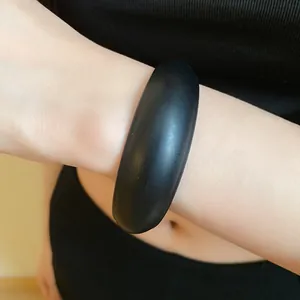 Close-up detailed view of a minimalist matte black resin round bangle worn on a model's wrist