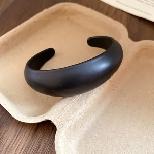 Close-up of a minimalist matte black resin cuff bracelet in eco-friendly packaging