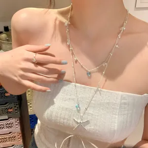 Detailed view of a layered silver starfish necklace worn with a white strapless top.