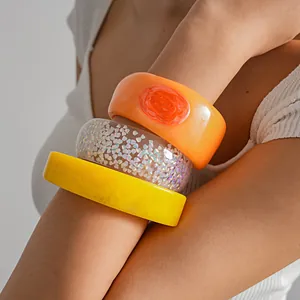 Close-up detail of three colorful resin bangles featuring glitter and marble textures