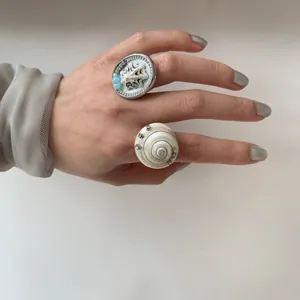 Close-up detail of unique minimalist seashell and spiral conch rings on a hand