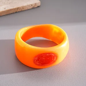 Close-up of irregular resin bangle featuring orange gradient and red marble detail