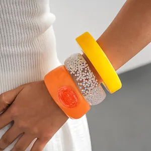 Detail view of chunky irregular resin bangles in vibrant yellow orange and glitter styles