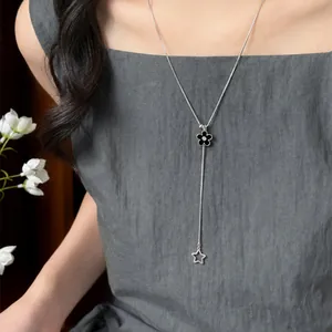 Elegant silver-toned Y-shaped necklace featuring a black flower and star charm pendant worn