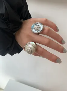 Close-up of hand wearing unique seashell rings with rhinestone accents