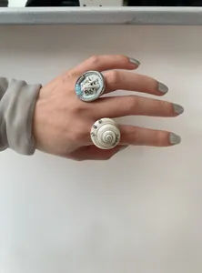 Detailed close-up showing unique seashell and spiral snail design rings worn on hand