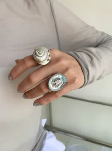 Close-up of minimalist rings featuring natural shell and crystal accents on a hand