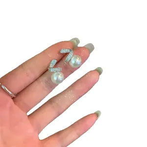 Elegant silver needle zircon pearl stud earrings with V-shape design shown on hand