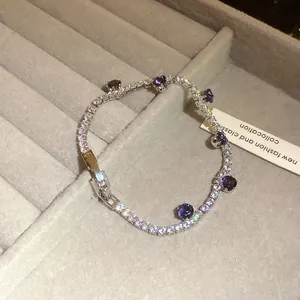 Detailed view of silver zircon bracelet with purple gemstones on grey display.