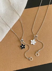 Close-up of black and white flower pendant adjustable necklaces on brown background