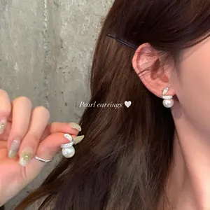 Close-up detail of elegant white pearl stud earrings with sparkling zirconia accents