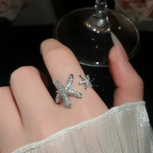 Primo piano di un anello aperto a forma di stella marina con zirconi brillanti.