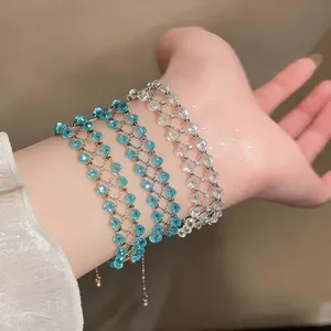 Detail view of three handmade openwork turquoise and clear beaded bracelets worn on a wrist