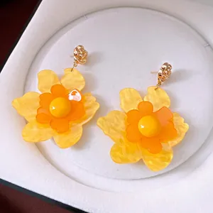 Pendientes de flores de resina amarilla vibrante con pétalos escalonados y tachuelas doradas