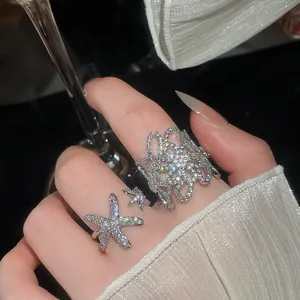 Dettaglio ravvicinato di anelli in argento con fiori traforati, stelle marine e zirconi