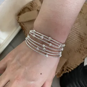 Dettaglio di bracciali in argento a strati con perle testurizzate indossati al polso