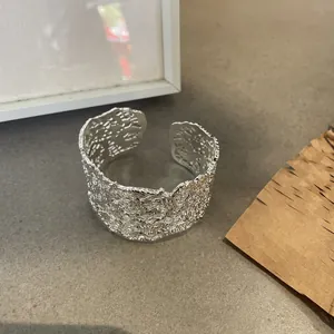 Vista dettagliata del bracciale rigido aperto minimalista con motivo floreale traforato