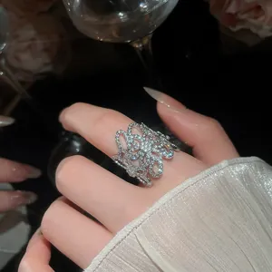 Macro di un elegante anello a fiore traforato in argento con zirconi su una mano
