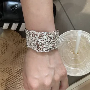 Dettaglio di un bracciale a polsino in argento traforato con intricato motivo a fiori