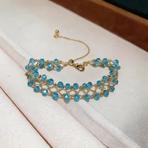 Macro detail of a handmade gold lattice bracelet with sparkling light blue crystal beads.