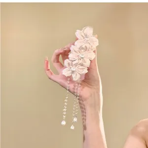 Close-up of an elegant pink fabric flower hair claw clip with long pearl beaded tassels