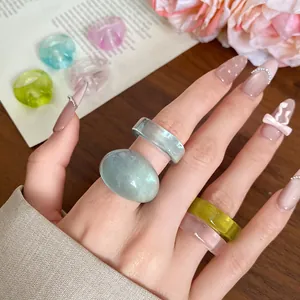 Close-up of hand wearing colorful resin rings in pastel blue, pink, and yellow