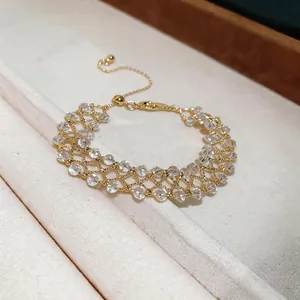 Detail showing a handmade gold hollow lattice bracelet with clear crystal beads