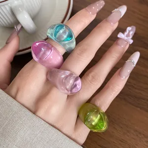 Detail view of four colorful irregular translucent resin rings worn on a manicured hand