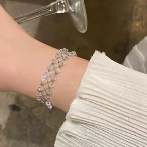 Detailed view of a handmade silver lattice bracelet with clear crystal beads on a woman's wrist