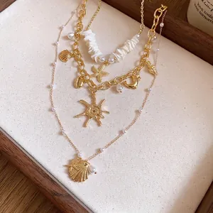 Elegante collana multistrato dorata con perle, conchiglie e ciondoli a stella marina