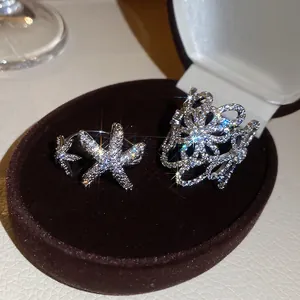 Primo piano di anelli scintillanti a forma di fiore e stella marina con zirconi