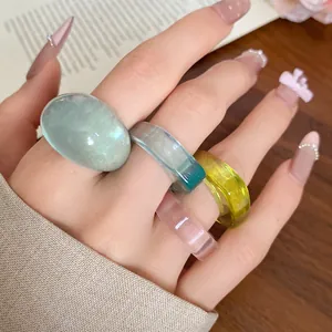 Detailed view of a four-piece set of colorful translucent resin rings worn on a hand