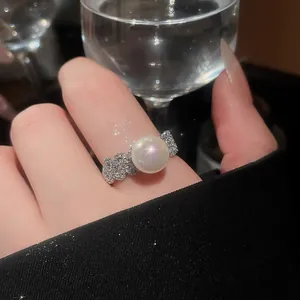 Detailed view of a French vintage zircon flower pearl open ring on an index finger