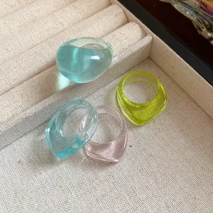 Close-up detail view of colorful resin irregular rings displayed in a linen jewelry tray
