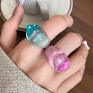 Close-up of vibrant blue and pink irregular resin rings worn on a hand